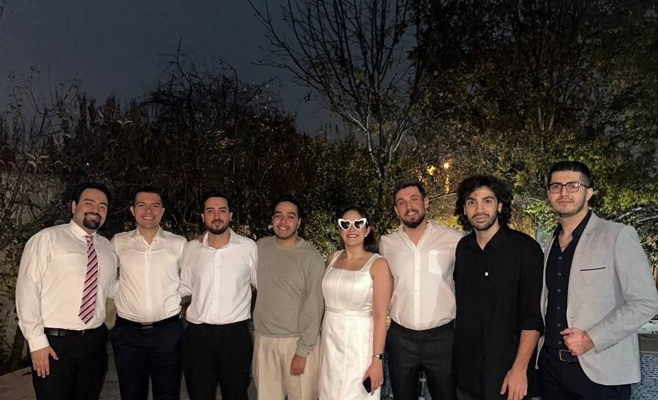 Eight friends dressed up in a row at night in a garden
