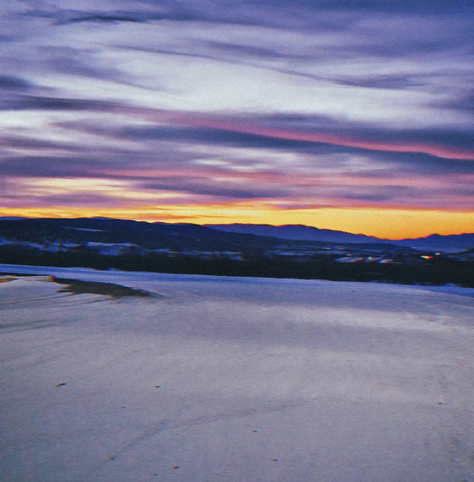 A purple and orange sunset over a snowy plain