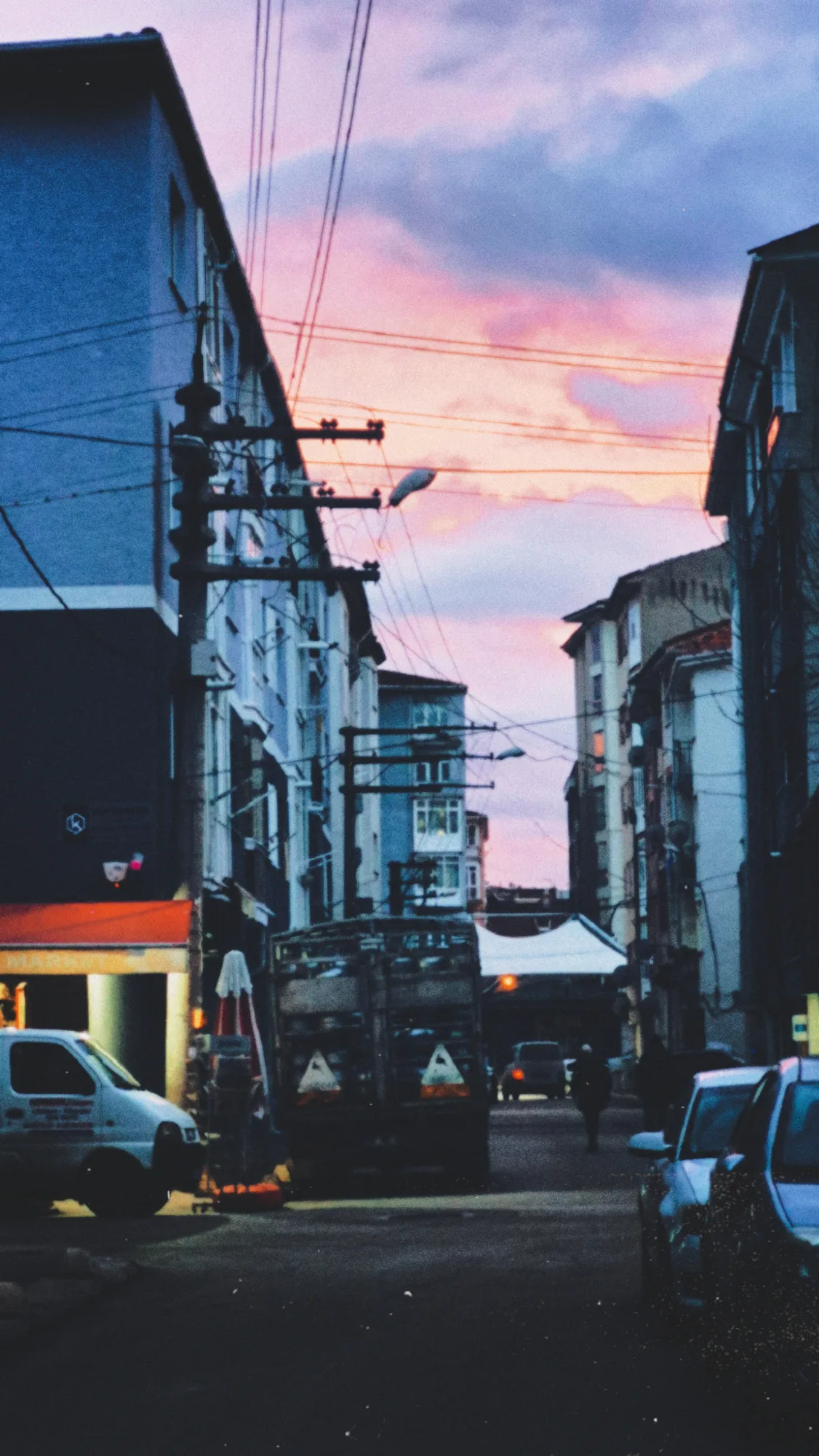 A street between apartment blocks under a pink evening sky