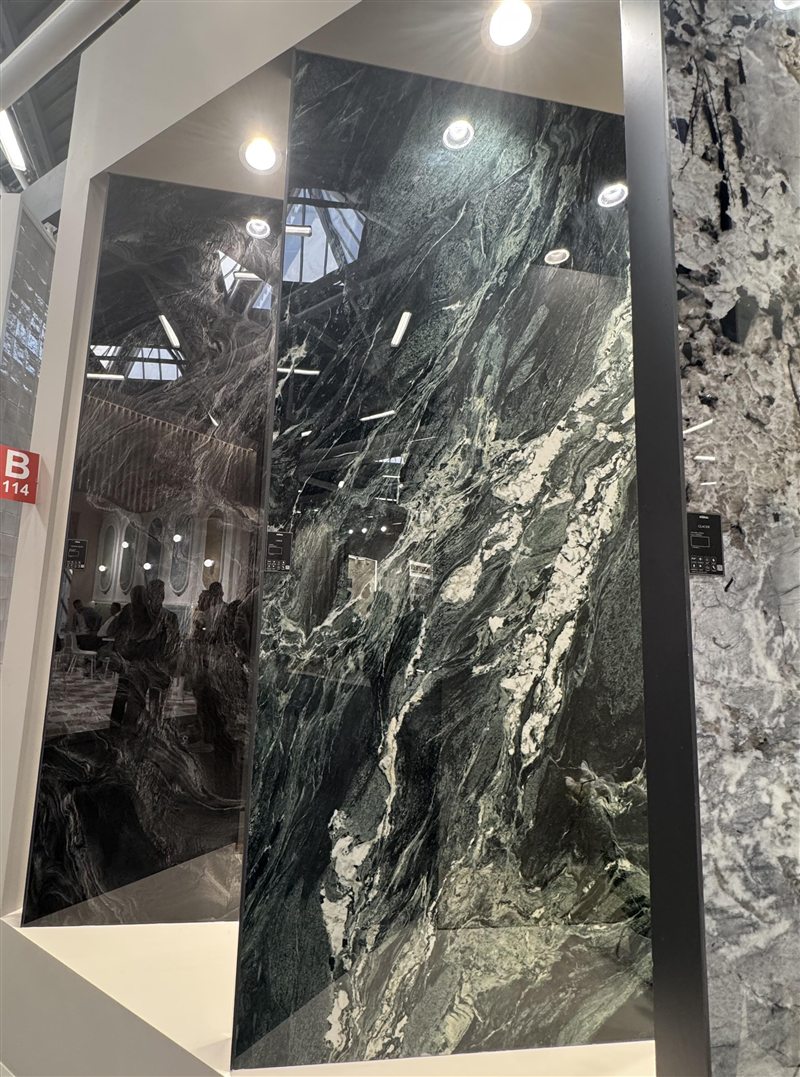Tall glossy panels of dark green marble-look stone with white veins at a trade-fair stand